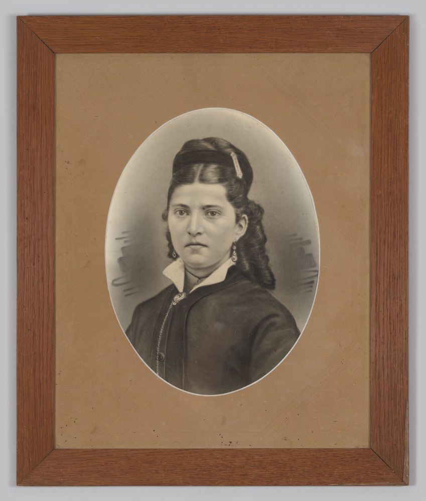 Portretfoto, in lijst, achter glas, voorstellende een jonge vrouw