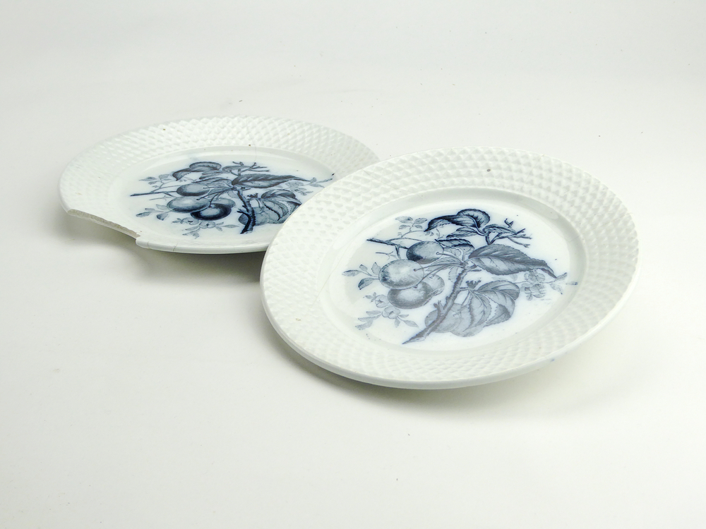 2 aardewerken ontbijtbordjes van het merk Petrus Regout & Co, Maastricht, decornaam Fruit, diameter 18 cm, 1 heeft groot stuk uit zijkant, op voorkant blauwe decoratie van 7 kersen aan een tak met bladeren, aan achterkant gemerkt met beeldmerk 71 A van Petrus Regout, blindmerk 6 en G, opgedoken door British Sub Aqua Club, Branch 501, ook wel de 501 Divers uit Folkstone, uit het wrak van de op 19 november 1887 na een aanvaring met het stoomschip Rosa Mary gezonken stoomschip W.A. Scholten, via hun woordvoerder Glyn Jones geschonken aan het Veenkoloniaal Museum.