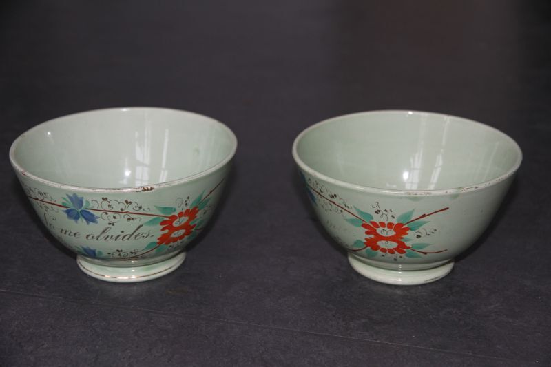 2 celadonkleurige kastkommen met oranjerode en blauwe bloemen met groene blaadjes, staand op standvoet. Op de ene kom staat in goud geschreven: Na me alvides (vergeet mij niet), op de andere kom staat: Corazon mia (mijn liefje). Ene kom onderkant gemerkt met blindmerk 8. Spaanse kastkommen, waarschijnlijk gemaakt in Engeland voor de Spaanse markt. Aangekocht bij antiquair Henk de Boer. Afkomstig uit de inboedel van schipper Gerrit de Jonge uit Groningen, die met zijn beurtschip veel in de Veenkolonien kwam en ze daar wellicht heeft opgescharreld.