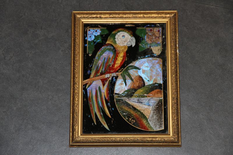 collage van vlindervleugels met afbeelding van een papegaai, de baai van rio de janeiro met de suikerbroodberg met kabelbaan. Door zeelui meegenomen uit Brazilie, in goudkleurige hout met gipsen lijst.