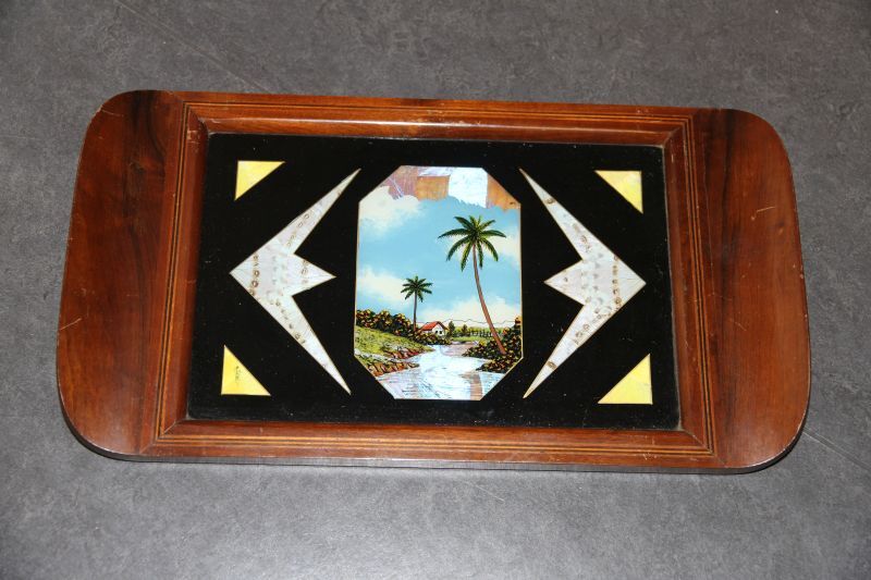 dienblad met onder de glasplaat een landschapje met rivier en palmbomen, deels geschilderd, deels een collage van vlindervleugels. Door zeelui meegenomen uit Rio de Janeiro.