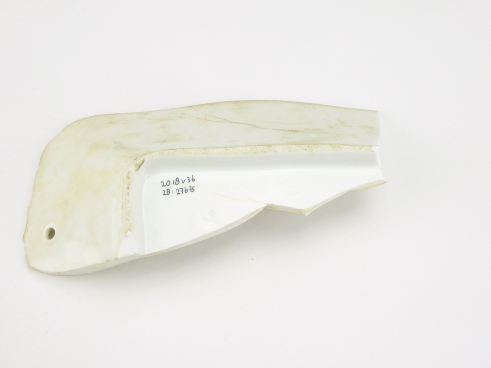 witte aardewerken scherf, waarschijnlijk afkomstig van een schaal, opgedoken door British Sub Aqua Club, Branch 501, ook wel de 501 Divers uit Folkstone, uit het wrak van de op 19 november 1887 na een aanvaring met het stoomschip Rosa Mary gezonken stoomschip W.A. Scholten, via hun woordvoerder Glyn Jones geschonken aan het Veenkoloniaal Museum.