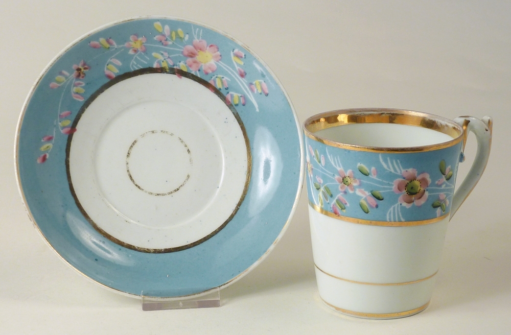 porseleinen kop en schotel in de kleuren blauw wit en goud, versierd met roze bloemdecoraties