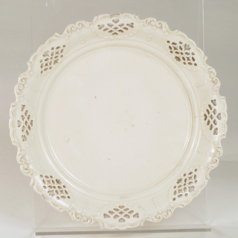 cremekleurige schotel met ajourwerk en bloemenrand en geschulpte rand