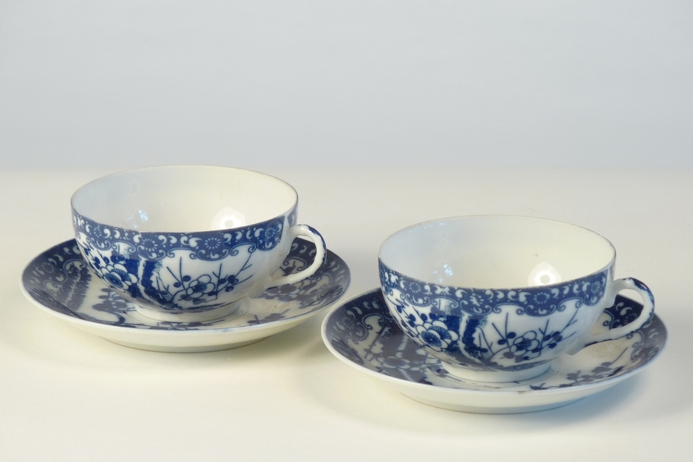 porseleinen kop en schotel gedecoreerd met blauw bloemmotief