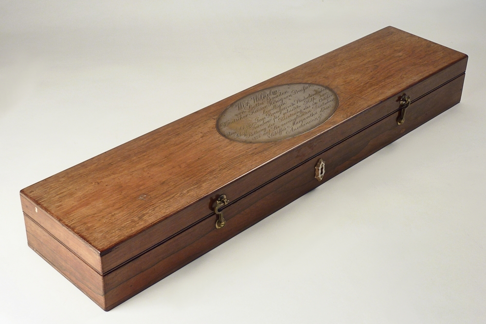 rechthoekige mahoniehouten kist met ovale zilveren plaat met inscriptie wir Willem von Gottes Gnaden Deutscher Kaiser , Konig von Preussen , bewilligen dem Schiffer Jan Brongers vom Niederlandischen Schiff Zwaluw fur geleistete Hilfe zur rettung der Besatzung des im Oktober 1875 auf See verungluckten Deutschen Schiffes Margaretha diese Anerkennung.