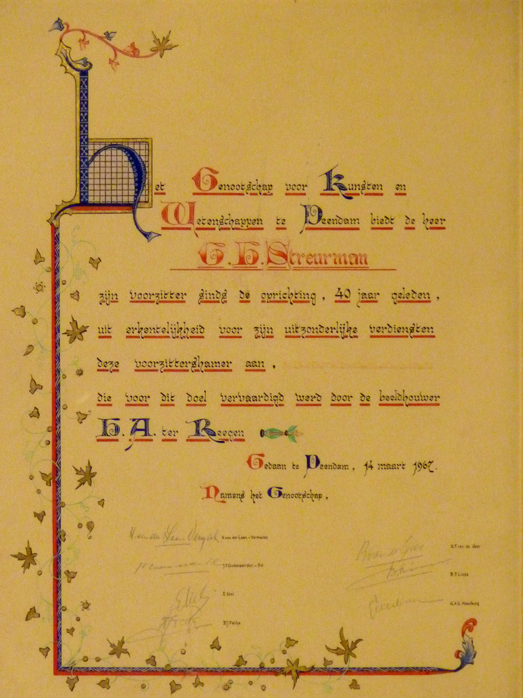 Gekalligrafeerde oorkonde door J.Visser te Den Haag bij voorzittershamer met tekst: Het Genootschap voor Kunst en Wetenschap te Veendam biedt de heer G.H. Streurman zijn voorzitter sinds de oprichting, 40 jaar geleden, uit erkentelijkheid voor zijn uitzonderlijke verdiensten deze voorzittershamer aan, die voor dit doel vervaardigd werd door de beeldhouwer H.A Ter Reegen. Gedaan te Veendam 14 maart 1967.