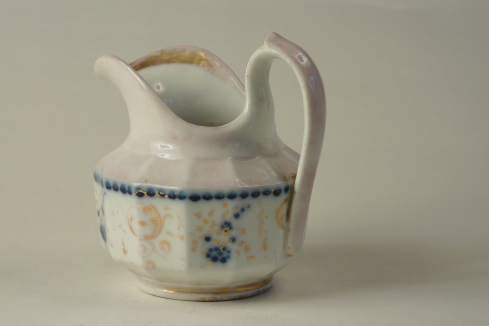 aardewerken melkkan met blauw en goudkleurige foglio en bloementrosdecoratie met voluutoor