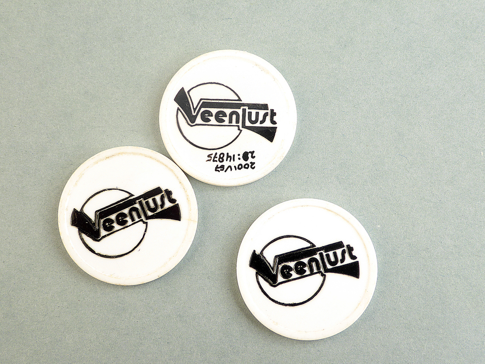 ronde witte plastic penning met aan weerszijden zwarte tekst Veenlust