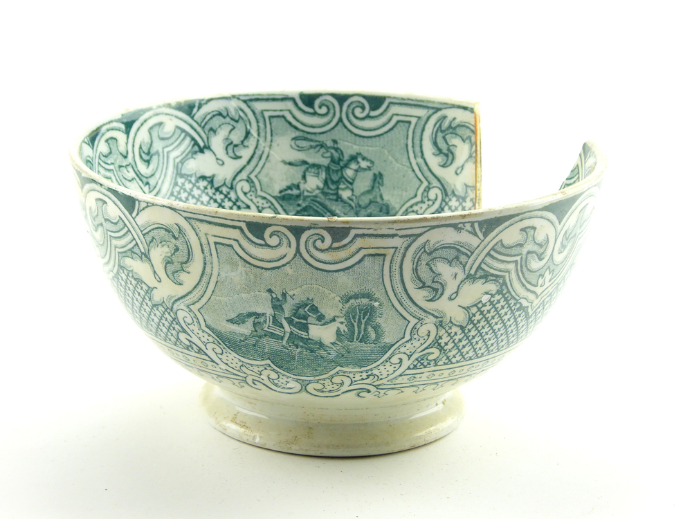 aardewerken kom op standvoet van het merk Petrus Regout & Co, Maastricht, decornaam Lasso, diameter 14,9 cm, op binnenkant 4 x groene decoratie van man op paard met lasso die paarden vangt, buitenkant groene decoratie van loslopende paarden en man op paard met lasso, scherf uit bovenrand, gemerkt met beeldmerk 71 A van Petrus Regout, opgedoken door British Sub Aqua Club, Branch 501, ook wel de 501 Divers uit Folkstone, uit het wrak van de op 19 november 1887 na een aanvaring met het stoomschip Rosa Mary gezonken stoomschip W.A. Scholten, via hun woordvoerder Glyn Jones geschonken aan het Veenkoloniaal Museum.