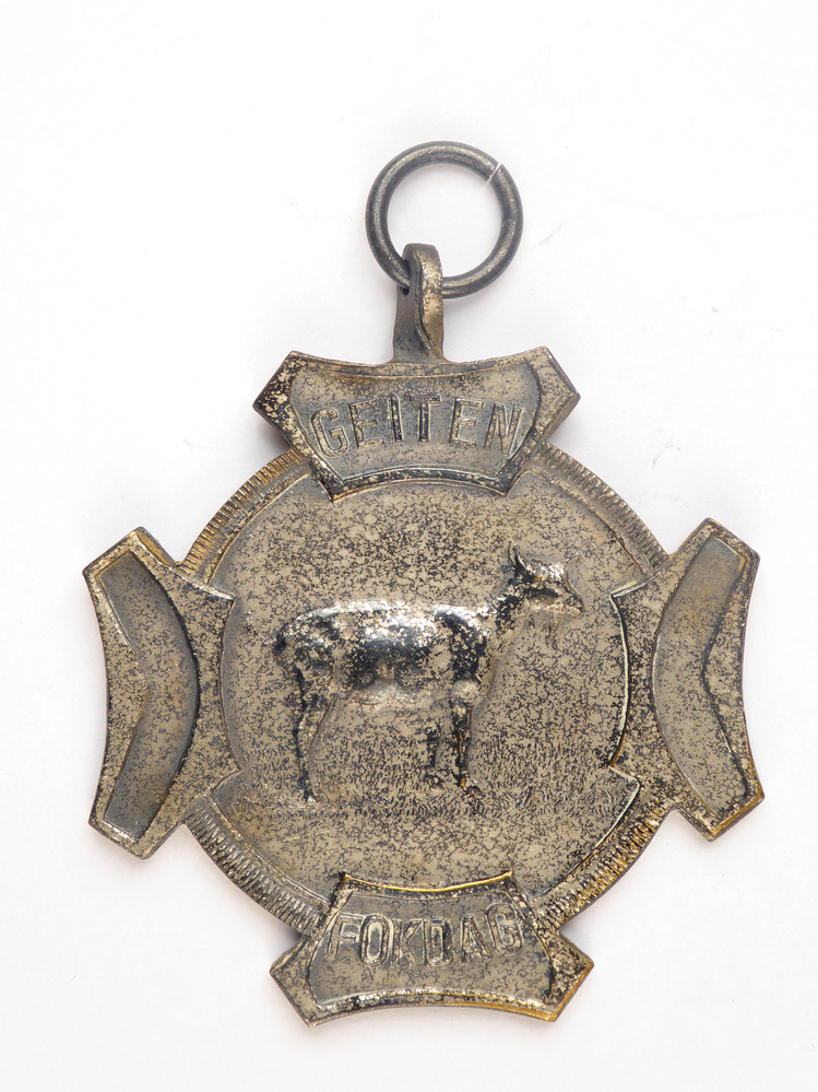 zilverkleurige medaille, aan vier kanten een soort oortje met op voorkant afbeelding van een geit en inscriptie geitenfokdag, aan achterkant inscriptie prov k 5-9-59 2B 4 j S 104 H Dijkstra