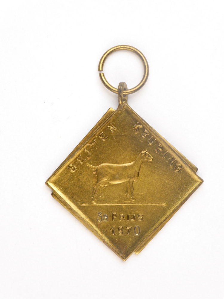 ruitvormige koperkleurige medaille met op voorkant afbeelding van een geit en inscriptie geiten keuring 3 A prijs 1970 en op achterkant inscriptie RvJ 6592