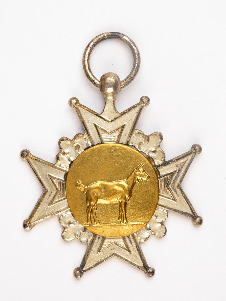 stervormige zilveren medaille met goudkleurige middencirkel met afbeelding van een geit en op achterkant inscriptie S 887 Res kamp 52