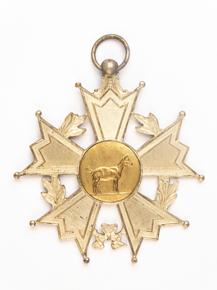 zilverkleurige stervormige medaille met op voorkant afbeelding van een geit, op achterkant inscriptie 1954 Kamp S 887 A.G.B.D. Fa J Repko Sneek