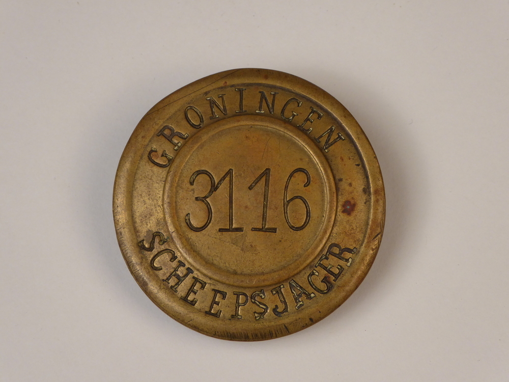 ronde messing scheepsjagerspenning met op voorkant geslagen inscriptie Groningen 3116 Scheepsjager. Scheepsjagerspenning afkomstig van Hendrik Spijker, geboren 14 juli 1886 te Veendam, overleden 18 november 1964 te Veendam. Hij is getrouwd met Betje Hut op 26 februari 1921 te Veendam, Groningen, hij was toen 34 jaar oud. De penning is uitgegeven in 1933, Hendrik was toen 47 jaar oud. Hendrik gebruikte deze penning voor zijn schip de Jonge Willem, 44 ton. Gebouwd door de firma Koster te Stadkanaal in 1929.