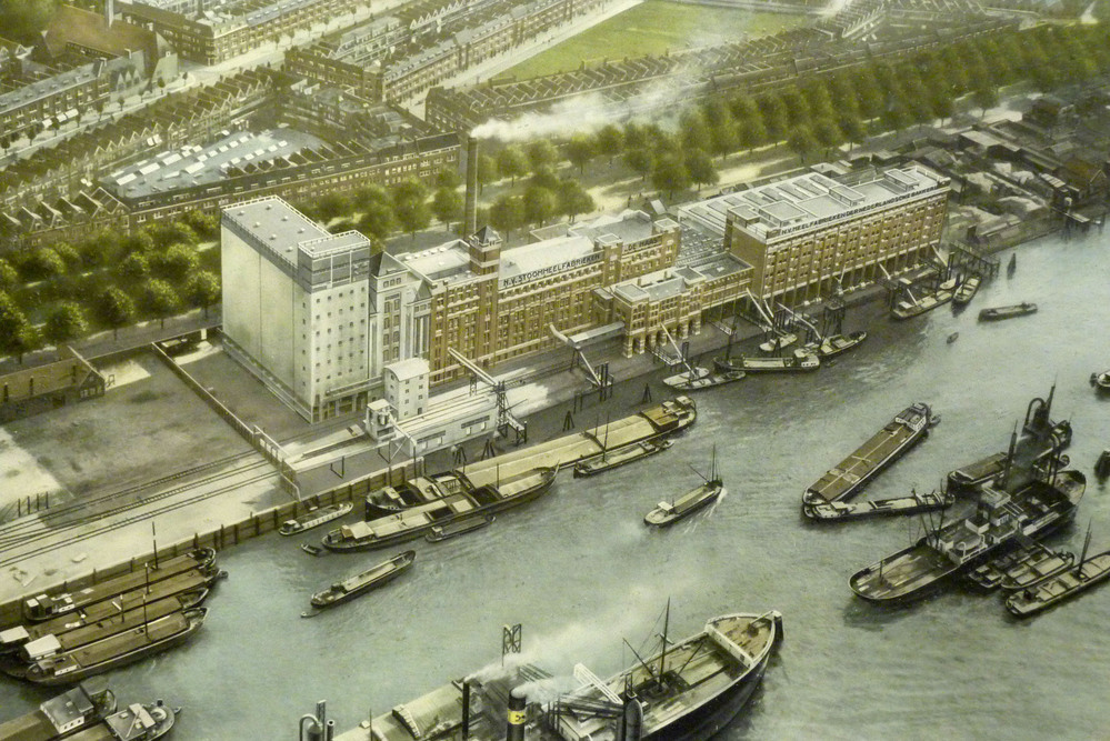 papieren gedenkplaat in houtn lijst met afbeeldig boten liggende voor een fabriek in het kanaal met opschrift 1915-1940 NV Meelfabrieken der Nederlandse Bakkerij