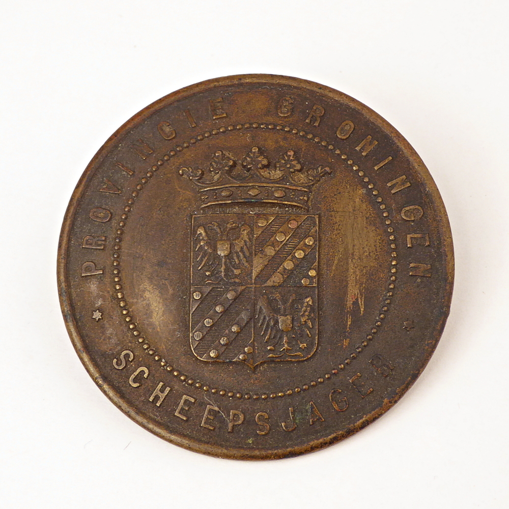 ronde messing scheepsjagerspenning met op voorkant randschrift Provincie Groningen Scheepsjager en wapen provincie Groningen, achterkant gegraveerd 1125 = Lammert de Vries, toen 28 jaar te Veendam.