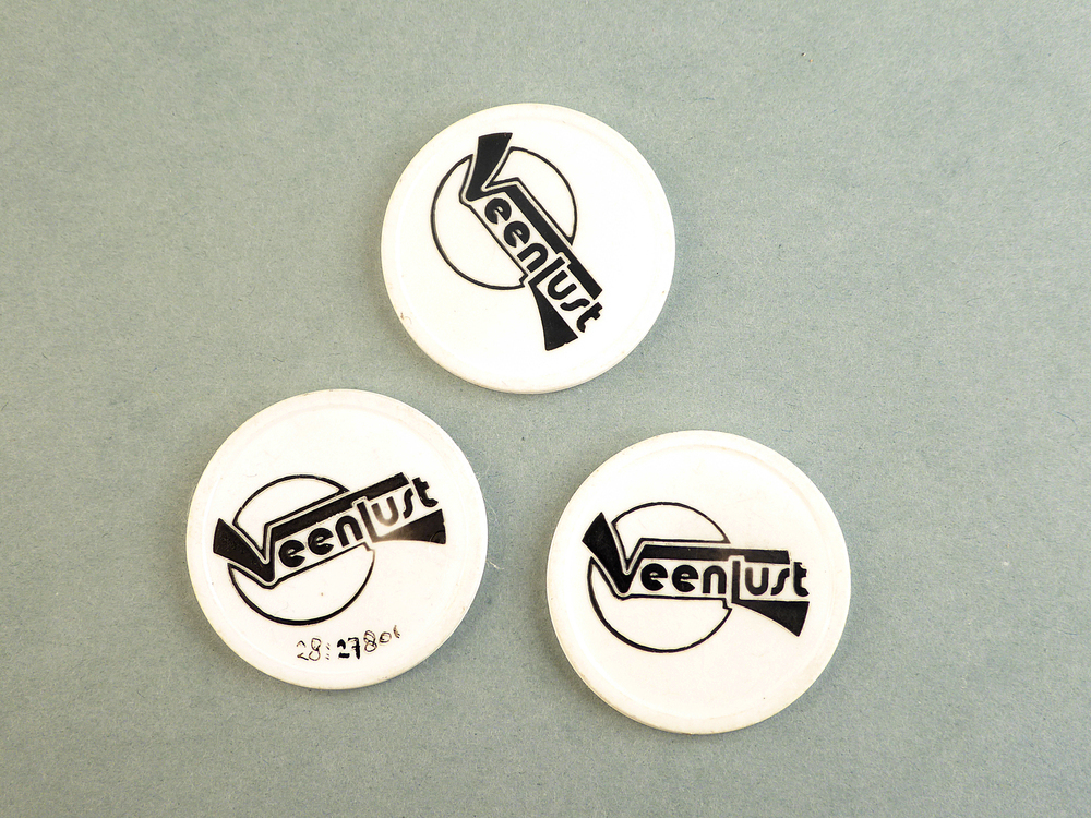 ronde witte plastic penning met aan weerszijden zwarte tekst Veenlust