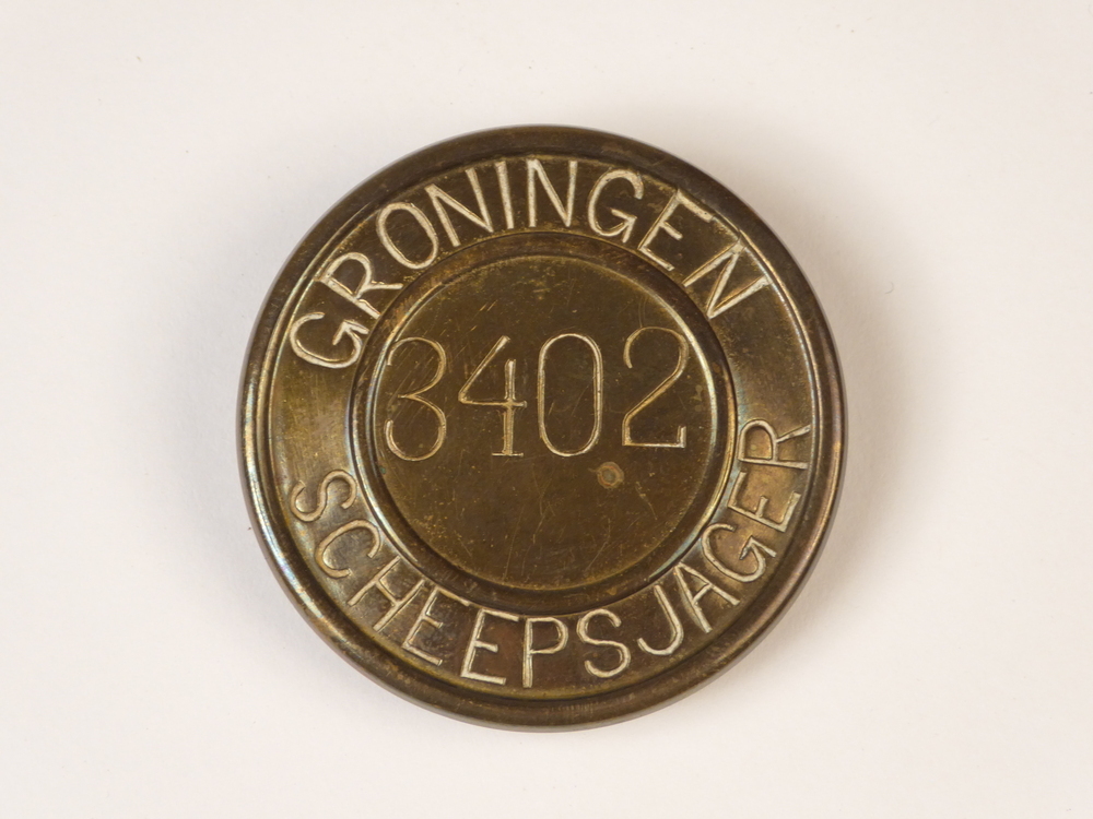 ronde messing scheepsjagerspenning, met op voorkant geslagen inscriptie Groningen 3402 Scheepsjager. Scheepsjagerspenning afkomstig van Harm van de Geize, landbouwer, geboren 13 december 1917 te Tange, gemeente Onstwedde, overleden 19 december 2003, gehuwd op 16 juli 1938 te Muntendam met Antje Meijer, geboren 26 oktober 1916, overleden 9 oktober 2016. Op het moment van uitgave van de penning was Harm van der Geize 26 jaar en woonde te Ommelanderwijk.