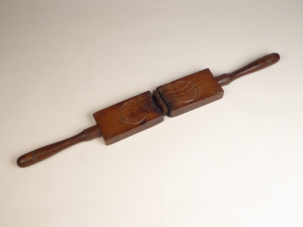 Dit voorwerp lijkt op een notenkraker, maar is het zeker niet. Het bestaat uit 2 onderdelen , die aan het uiteinde, met een ijzeren, verzonken scharnier zijn verbonden. Elk stuk is 30,5 cm lang, en 7 cm breed, en bestaat uit een rechthoekig gedeelte met een gedraaide langwerpige handgreep. 2,5 cm voor de scharnier bevindt zich een cirkelvormige inkeping. Het cirkelvormig oppervlak is iets hol, ongeveer een a twee mm. Bij het scharnier is het voorwerp lichtelijk verbrand, en zal dus in een hete omgeving hebben gelegen of zijn gebruikt. Het is een botermal, om boterfiguurtjes mee te maken. In dit geval eenvoudige rondjes die makkelijk smeerbaar zijn.