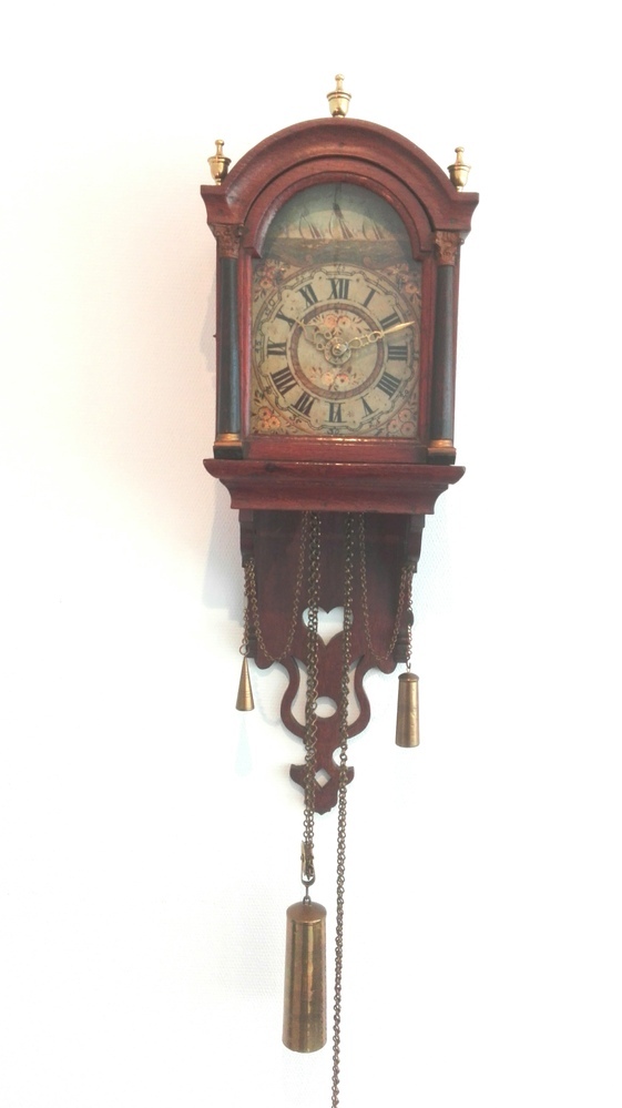 De eikenhouten kast van deze klok is traditioneel van vorm met een afneembare getoogde kap met glasdeur met aan de voorkant links en rechts twee pilaren. In de staart is een hartvormig gat uitgezaagd. De bovenzijde van de kap wordt gesierd door drie messing vazen. De ijzeren wijzerplaat is geheel wit en beschilderd. In de toog is een meertje geschilderd met zeilschepen, terwijl in de hoeken vier bloemdecoraties zijn afgebeeld. In het centrum zijn ook twee bloemdecoraties zichtbaar. De tijd wordt aangegeven door middel van twee opengewerkte messing wijzers op een cijferring met Romeinse cijfers. Waarschijnlijk als huwelijkscadeau gegeven door de familie Bulthuis bij het huwelijk van Si(e)men van Zanten, turfschipper en Geertruida Bulthuis op 07-05-1859 te Usquert. Hing altijd in het roefje van hun tjalk “de vrouw Geertruida”, gebouwd te Stadskanaal.  De schippersklok bleef aan boord van het turfschip. Eenmaal op de vaste wal namen ze de klok mee naar hun woning in Middelstum. Na het overlijden van Si(e)mon van Zanten op 12 augustus 1896 te Middelstum ging de tjalk bij boedelscheiding in 1897 naar de zoon Derk van Zanten, in hetzelfde jaar gehuwd met Anje Poel. Derk van Zanten, geboren 7 januari 1866 te Kantens, overleden 2 november 1951 te Middelstum, getrouwd op 22 mei 1897 te Middelstum met Anje Poel, geboren 31 januari 1875 te Warfum, overleden 14 mei 1964 te Middelstum. Geertruida Bulthuis hertrouwd met Jacobus Mulder en overlijdt op 22 maart 1922 te Middelstum. Het huwelijk van Derk en Anje bleef kinderloos. Na het overlijden van Anje Poel kocht schenker in 1967 de staartklokschipper van haar broer Sebo Poel te Delfzijl voor f 1500,-. Sebo was de executeur van de boedelafwikkeling. Schenkers grootmoeder Jantje van Zanten was ook een dochter van Si(e)mon van Zanten en Geertruida Bulthuis en getrouwd met grootvader Freerk Bonne Harkema en dus een zuster van Derk van Zanten.  JANTJE VAN ZANTEN, geboren 22-06-1871 te Middelstum, overleden 15-11-1958 te Assen, dochter van Siemon van Zanten (turfschipper) en Geertruida Bulthuis; Gehuwd 26-10-1895 te Middelstum met Freerk Bonne Harkema (koopman), geboren 30-05-1873 te Bedum, overleden 18-01-1947 te Assen, zoon van Pieter Harkema (landgebruiker, koopman) en Jantje Venema.