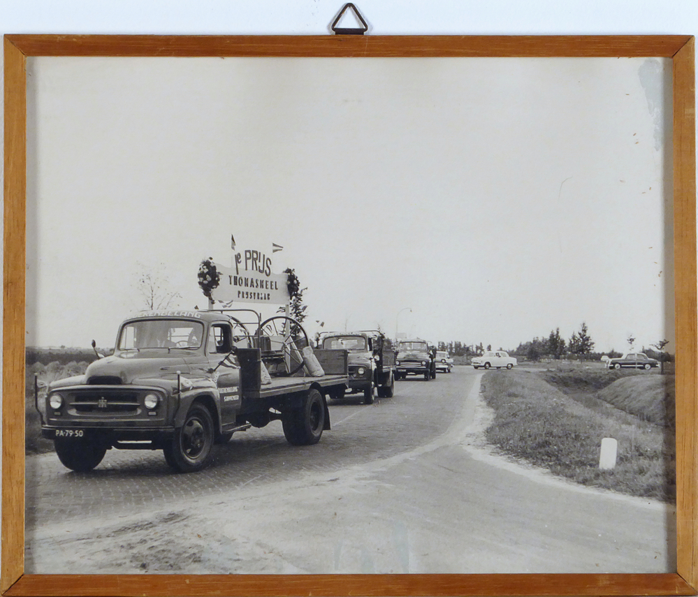 foto in houten lijst met daarop een colonne vrachtauto's voorop rijdt een international harvester vrachtauto van coop boerenbelang te Sappemeer met kentekennummer PA-79-50, met op de laadbak een bord met daarop 1e prijs Thomasmeel prijsvraag, afkomstig van de COBO ( Cooperatieve Aan- en Verkoopvereniging Boerenbelang( opgericht in 1940 als Boerenbelang G.A. te Sappemeer, in 1965 door het samengaan van Coöperatie Noord-Oost te Veendam en Coöperatie Boerenbelang te Sappemeer gefuseeerd tot COBO, fuseerde met de aankoopcentrale in 1983 tot ACECO bv, fuseerde weer in 1990 tot ACM en in 2010 tot AGRIFIRM) te Hoogezand aan de van Neckstraat.