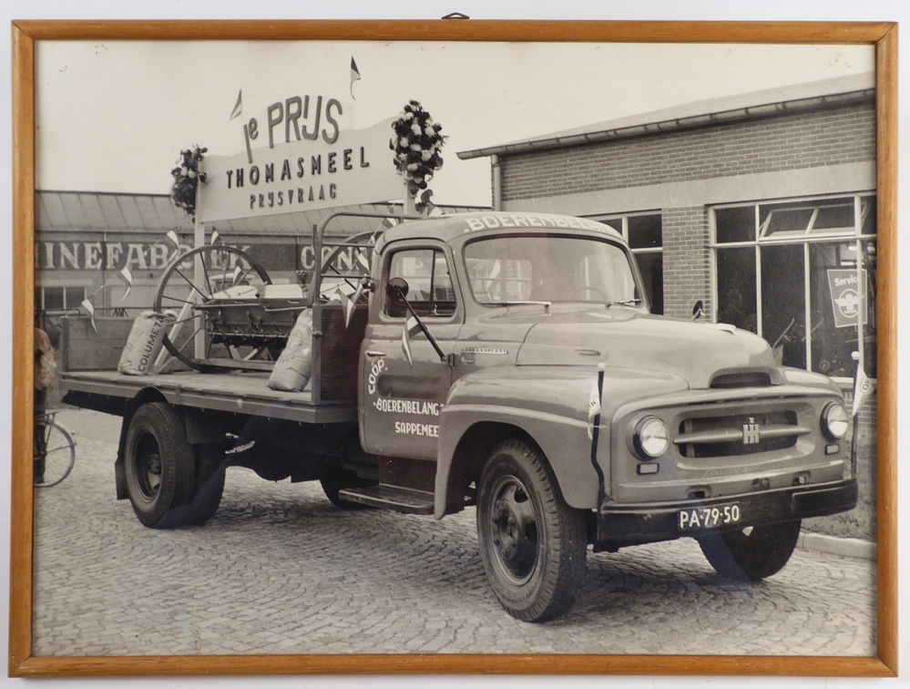 foto in houten lijst met daarop een een international harvester vrachtauto van coop boerenbelang te Sappemeer met kentekennummer PA-79-50, met op de laadbak een wat lijkt op een zichtmachine en bord met daarop 1e prijs Thomasmeel prijsvraag, afkomstig van de COBO ( Cooperatieve Aan- en Verkoopvereniging Boerenbelang( opgericht in 1940 als Boerenbelang G.A. te Sappemeer, in 1965 door het samengaan van Coöperatie Noord-Oost te Veendam en Coöperatie Boerenbelang te Sappemeer gefuseeerd tot COBO, fuseerde met de aankoopcentrale in 1983 tot ACECO bv, fuseerde weer in 1990 tot ACM en in 2010 tot AGRIFIRM) te Hoogezand aan de van Neckstraat.