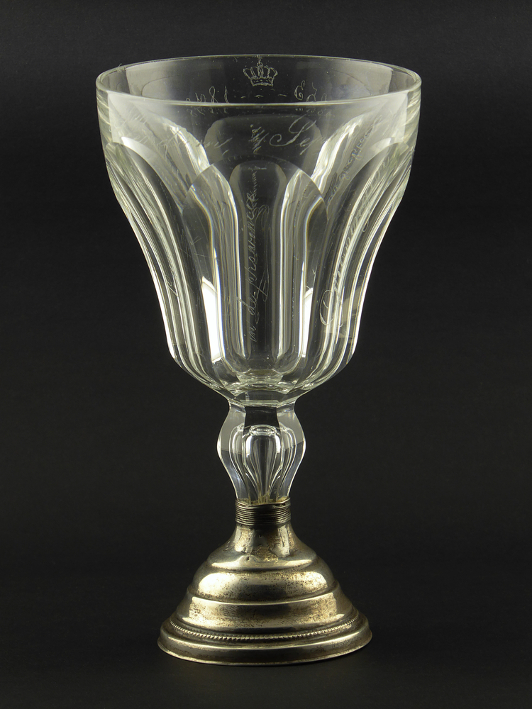 wijnglas, kristal met ronde zilveren voet met houten onderkant, 6 geslepen vlakken met afgeronde bovenkant, rondom gegraveerd T. Borgesius, De Maatschappij van landbouw in de provincie Groningen voor haren stichter, rondom bovenrand inscriptie 1853, kroon 1878 Veendam 4 sept 1878, rondom voetrand gehalteteken liggend zwaardje 1814 – 1905 en merk ?B = Hoogst waarschijnlijk Herman Barends, zilversmid Veendam 1855 – 1902.