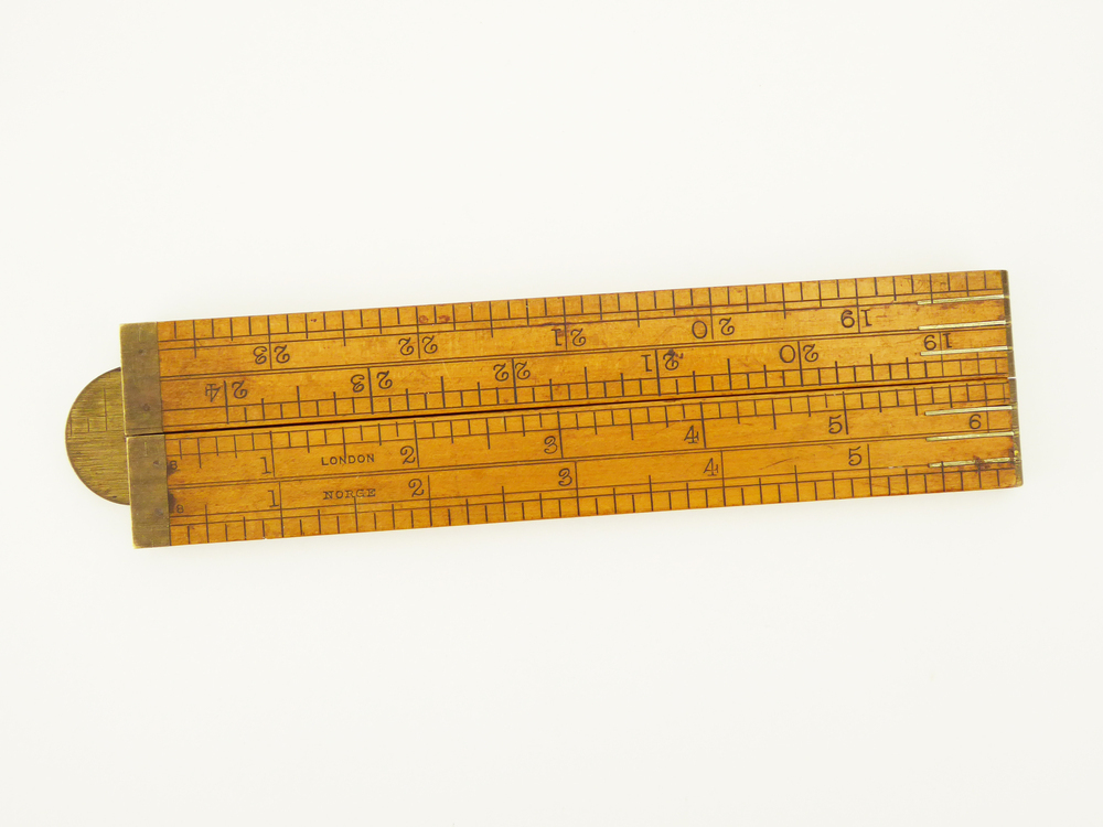 langwerpige buxushouten meetlat bestaande uit 4 scharnierende delen, op de uiteinden versterkt met messing, met op voorkant Amsterdamse schaalverdeling 1 cm - 62 cm, op achterkant Londense schaalverdeling 1 inch - 24 inch (1 inch = 2,54cm) en Noorse inch 1 - 23 (1 Noorse inch = 2,61 cm). Afkomstig uit de familie Everts, directeuren houthandel Meihuizen , Wildervank