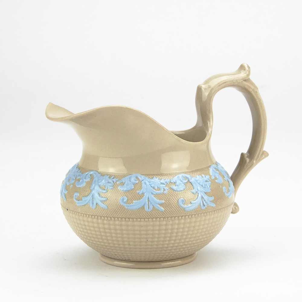 aardewerken roomkan, engels, bruin met in relief blauwe geverfde bladdecor, rondom onderkant ribbeltjes, voluutoor, lange dunne schenklip