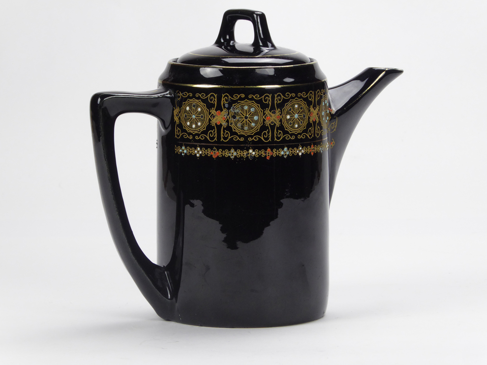 donkerbruin tegen zwart aan aardewerken theekan, waarschijnlijk gemaakt in Japan, geometrische goudkleurige motieven , handbeschilderd met emaillen florale motieven, gemerkt aan onderkant met 3 blauwe emaillen stippen, ronde deksel met rechthoekige handgreep, korte tuit, oor is halfgebogen, aan bovenkant recht, afkomstig van zeevarende veenkoloniale familie