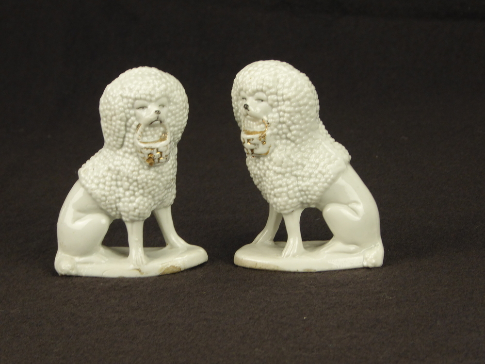 2 zittende steengoed poedels op onderplaat, met goudkleurige korf in hun bek