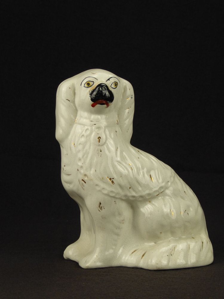 witte steengoed hond, goudkleurige decoratie compleet afgesleten, voorpoten vast aan lichaam, gele ogen, roze snuit, ietwat onhandige mond