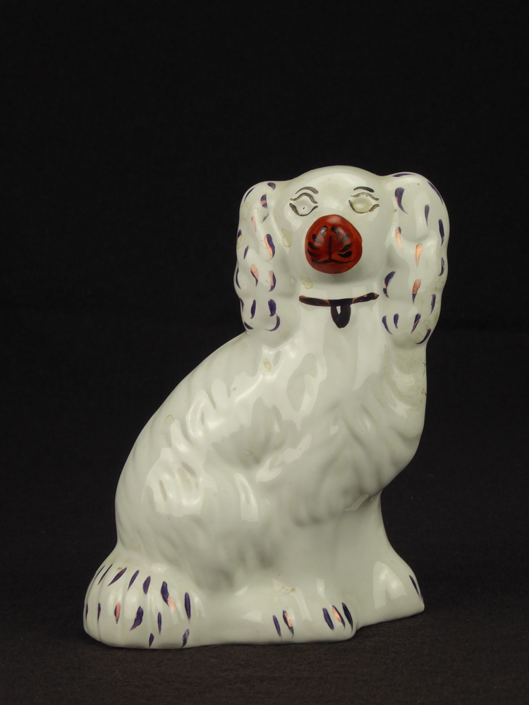 witte steengoed hond, geen gegoten ketting en hangslot, de glazen ogen missen, de decoraties zijn in koperlustre rechtstreeks op het lichaam aangebracht