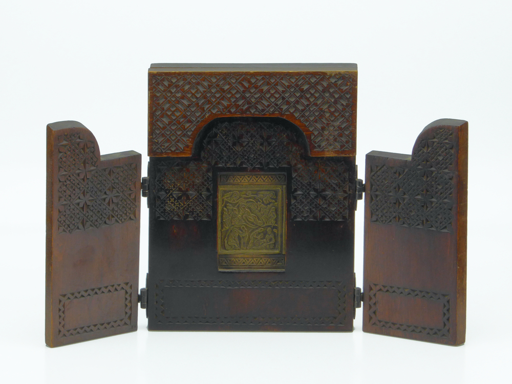 messing of bronzen icoon met afbeelding geboorte van jezus, de drie wijzen, ster met Russische inscriptie, omvat door een houten behuizing in de vorm van een boek, 2 houten luikjes met ijzeren scharnieren om het geheel te sluiten, aan de binnenkant versierd met ruitvormige patronen met uitgesneden motiefjes, aan onderkant cartouche met zigzaglijn, aan de buitenkant deurtjes ruitvormig motief en zigzaglijn.