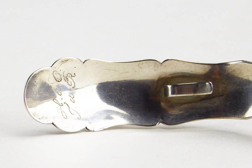 roomlepeltje. De steel is gebogen en heeft een mooie fijne stippel bloemdecoratie met bovenaan een geometrisch motief. Steel gedecoreerd met een bolletje / knop. Op de achterkant van het roomlepeltje zit een haakje. Meesterteken: G 5 = Willem Hermannus Groenier (Veendam) meestertekens 1848 - 1890 belastingteken zeepaardje 1859 - 1893, Lengte: 12 cm. Aan achterkant steel gegraveerd H de G J de R