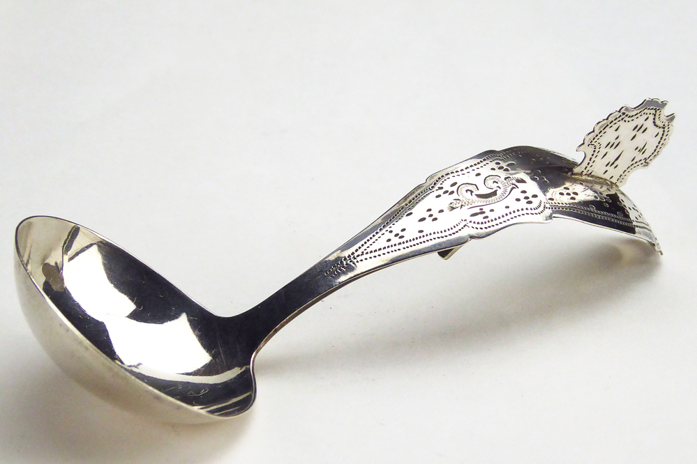 roomlepeltje. De steel is gebogen en heeft een mooie fijne stippeldecoratie met bovenaan en onderaan een geometrisch motief. Steel gedecoreerd met een kam. Op de achterkant van het roomlepeltje zit een haakje. Meesterteken: G 5 = Willem Hermannus Groenier (Veendam) meestertekens 1848 - 1890, gehalteteken leeuw en minervahoofd. lengte 11,5 cm