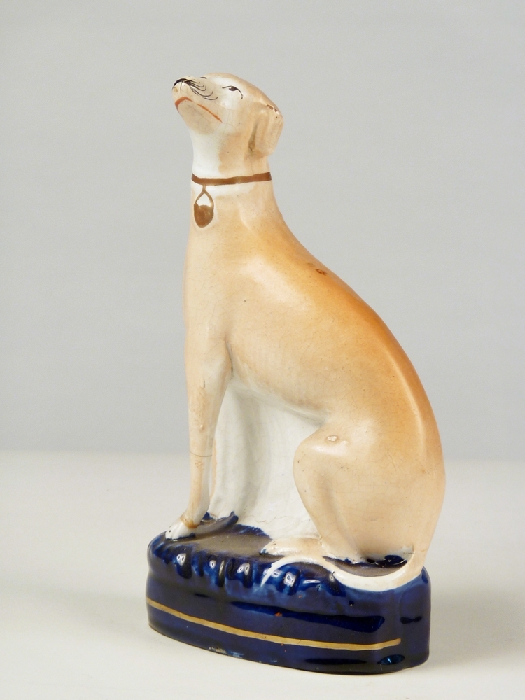 oranje bruinige italiaanse greyhound / windhond van Engels steengoed op blauwe voetstuk met gouden bies, 11 x 6,5 x 21 cm, Staffordshire, ongeveer 1850. Full of expression and self importance .