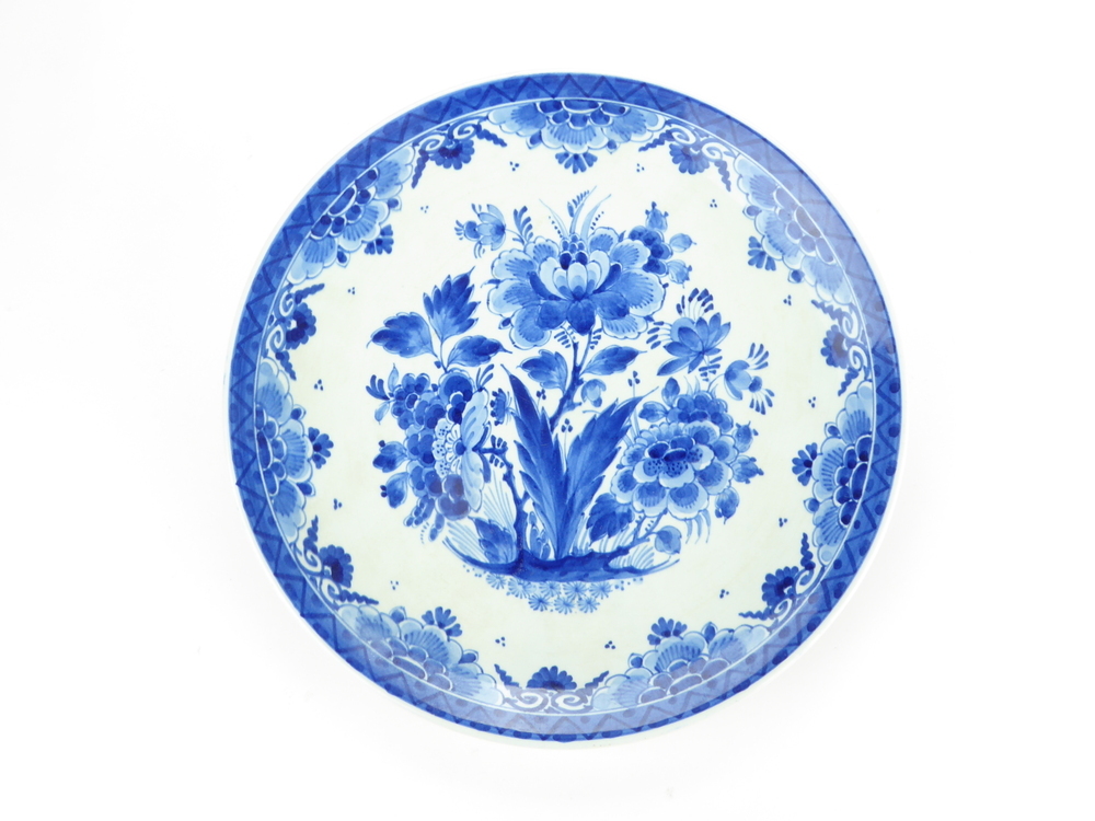 ronde delfts blauwe aardewerken bord met op binnenkant florale decoratie, aan achterkant inscriptie Ceres 1915 - 1965, logo De Porceleijne fles met initialen JT en Delft, gemerkt H d J (ceramist H. de Jong  werkzaam van 1951 - 1984) modelnummer 1144 jaarletters CJ = 1965, aangeboden aan de directie van strocartonfabriek Ceres bij het 50 jarig bestaan