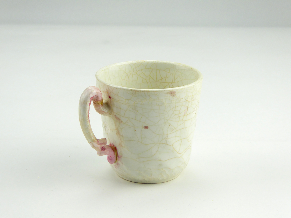 Klein wit aardewerken kopje, diameter bovenrand 6,7 cm, zonder schotel met roze / bruinige vlekjes aan oortje, onderop in zwartgroen gemerkt Nederlandse leeuw met rondschrift Societe Ceramique Maestricht en niet te lezen inscriptie, opgedoken door British Sub Aqua Club, Branch 501, ook wel de 501 Divers uit Folkstone, uit het wrak van de op 19 november 1887 na een aanvaring met het stoomschip Rosa Mary gezonken stoomschip W.A. Scholten, via hun woordvoerder Glyn Jones geschonken aan het Veenkoloniaal Museum. Waarschijnlijk gebruikt door de bemanning van het stoomschip W.A.Scholten.