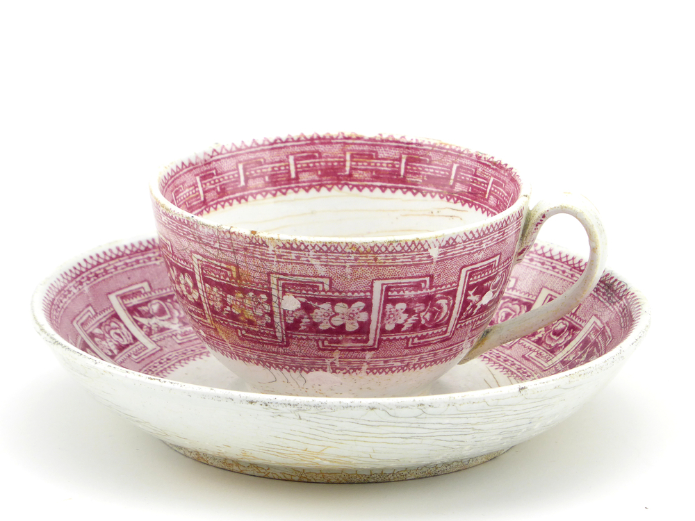 aardewerken kop en schotel van het merk Petrus Regout & Co, Maastricht, kop diameter 8 cm, schotel diameter 13,5 cm, op buiten en binnenkant rode decoratie van bloemen en wolfsangel, blindmerk 4, gemerkt met beeldmerk 71 A van Petrus Regout, schotel decornaam Border, opgedoken door British Sub Aqua Club, Branch 501, ook wel de 501 Divers uit Folkstone, uit het wrak van de op 19 november 1887 na een aanvaring met het stoomschip Rosa Mary gezonken stoomschip W.A. Scholten, via hun woordvoerder Glyn Jones geschonken aan het Veenkoloniaal Museum.