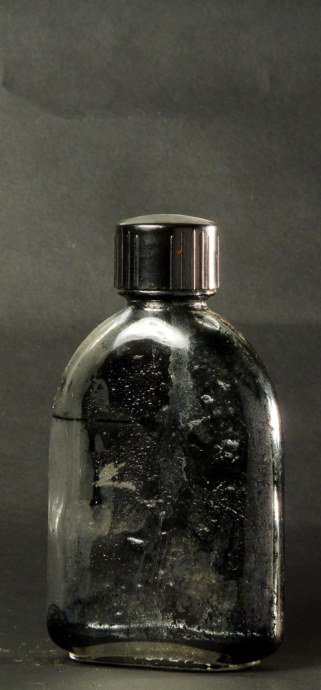 glazen fles met kunststoffen dop, aan onderkant gegoten V.M.