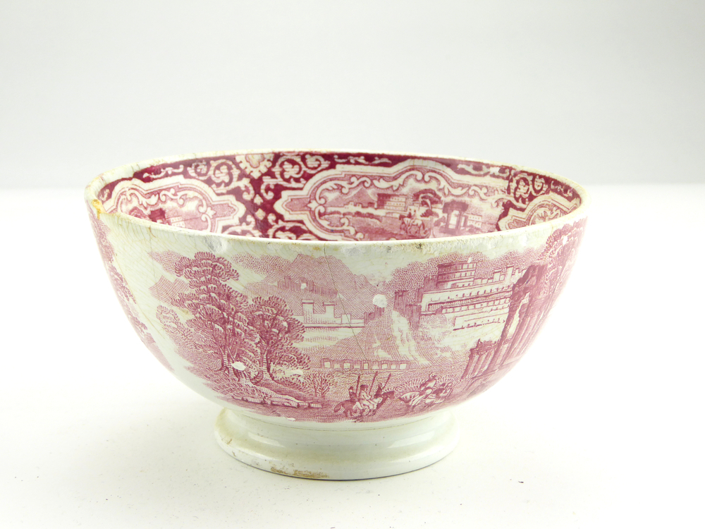 aardewerken kom op standvoet van het merk Petrus Regout & Co, Maastricht, decornaam Samarcand, diameter 14,9 cm, op binnenkant rode decoratie van mannen op paarden met lansen, mensen, bomen en op achtergrond tempelzuilen en een stad, 3 losse scherven uit zijkant, gemerkt met beeldmerk 71 A van Petrus Regout, opgedoken door British Sub Aqua Club, Branch 501, ook wel de 501 Divers uit Folkstone, uit het wrak van de op 19 november 1887 na een aanvaring met het stoomschip Rosa Mary gezonken stoomschip W.A. Scholten, via hun woordvoerder Glyn Jones geschonken aan het Veenkoloniaal Museum.