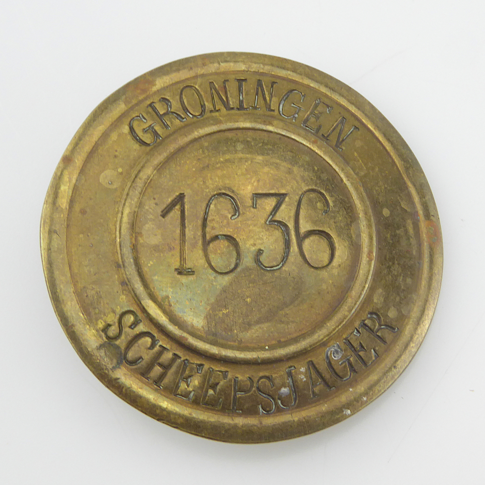 ronde messing scheepsjagerspenning, met op voorkant geslagen inscriptie Groningen 1636 Scheepsjager. Scheepsjagerspenning afkomstig van Albert Zuur, 35 jaar uit Veendam. Dit kunnen er 2 zijn, Albert Zuur, geboren 2-1-1906 te Usquert, zoon van Jan Zuur en Janna Meedendorp, of Albert Zuur, geboren 17-4-1913 te Stadskanaal, gemeente Wildervank, zoon van Hendrik Zuur en Grietje Hoven. 1906 + 35 jaar = 1941 of 1913 + 35 jaar = 1948.