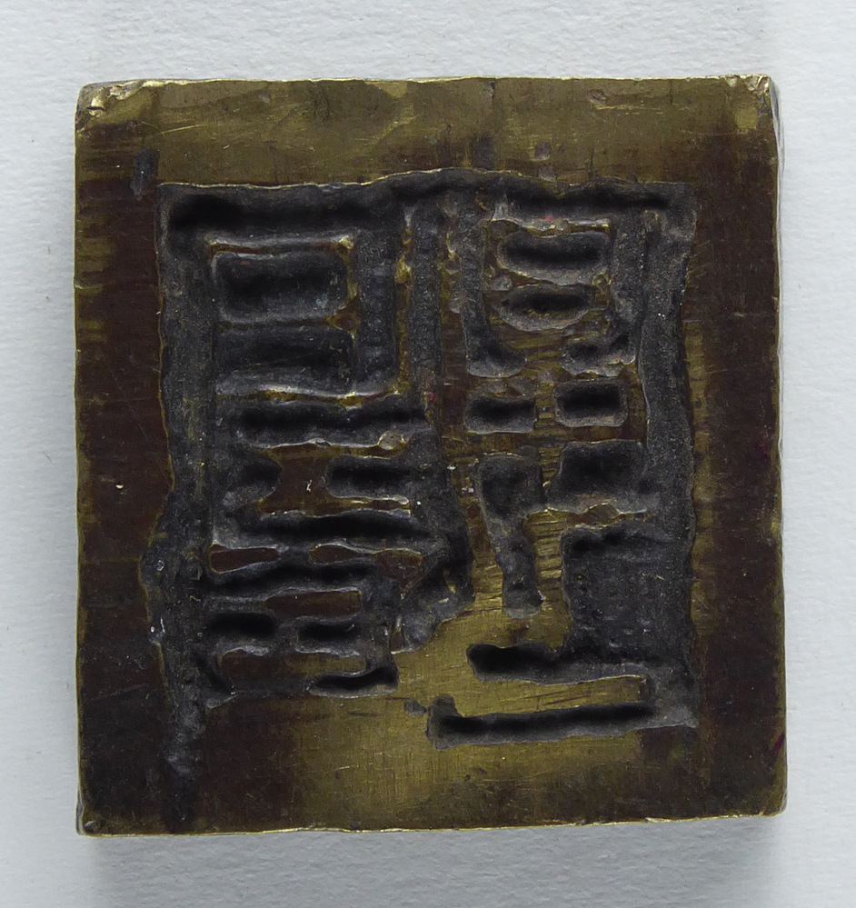 dikke vierkante messing cliche met afbeelding chinese lettertekens, afkomstig van kantoorinstallaties Bv Schuur te Veendam