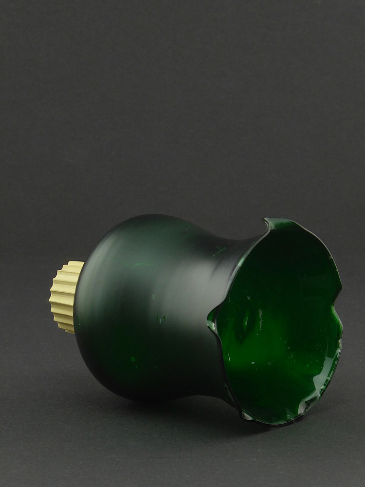 groene glazen klokvormige object met onderaan geschulpte rand en boven steeltje, met hier omheen een lichtbruine rubberen ring