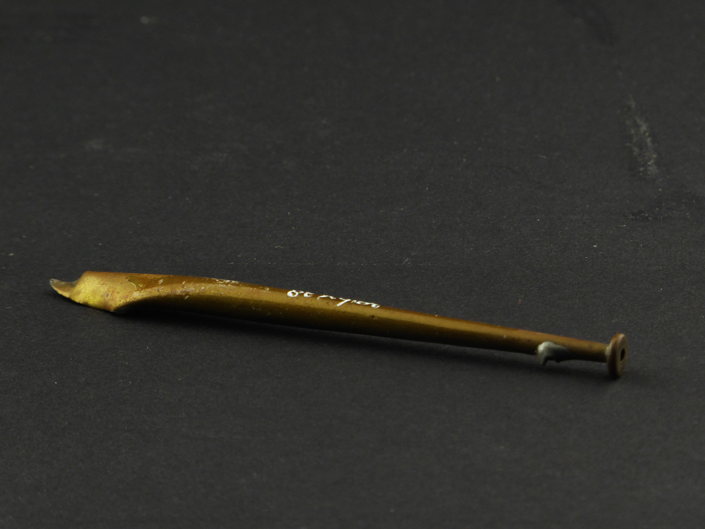 langwerpige messing steeltje met aan uiteinde een knop, andere uiteinde is breder, open en spits en verwrongen