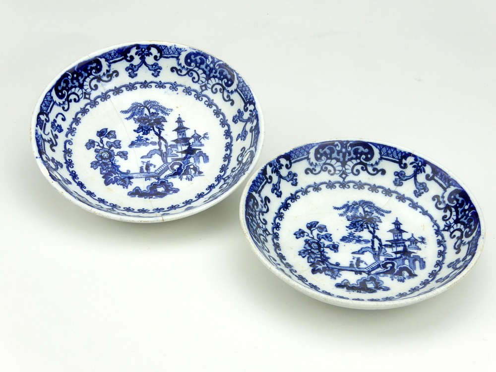 aardewerken schotel van het merk Petrus Regout & Co, Maastricht, schotel diameter 13,5 cm, op binnenkant blauw decoratie van bloemen, bomen, een man op een loopbrug loopt langs een zittende man, op de achtergrond een pagode, schotel gemerkt met beeldmerk 71 A van Petrus Regout, schotel decornaam Pekin, opgedoken door British Sub Aqua Club, Branch 501, ook wel de 501 Divers uit Folkstone, uit het wrak van de op 19 november 1887 na een aanvaring met het stoomschip Rosa Mary gezonken stoomschip W.A. Scholten, via hun woordvoerder Glyn Jones geschonken aan het Veenkoloniaal Museum.