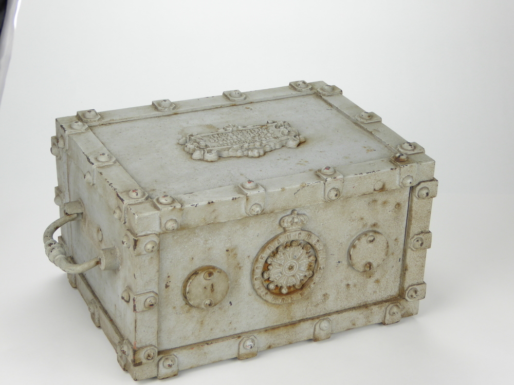 rechthoekige grijzgeverfde gietijzeren safe met 2 handgrepen, geheel bezet met stukjes ijzer vastgezet met schroeven. Op bovenkast gegoten inscriptie Incombustible Systeme Bauche / Brevete / S.G.D.G./ Usine A Guex Marne, aan voorkant slot met verdraaibaar slotplaat en fakelock en wapenschild met inscriptie S 1 B 6 5 Bauche 7 4 2 9 OBETE  met hierin draaibaar wiel, bovenop een kroontje, ongeveer 1865. In dit soort kluisjes werd tijdens transport waardevolle zaken veilig bewaard. Ijzeren scheepsgeldkist van Franse makelij met cijferslot, afkomstig van kapitein Harm A Hoetjer, via vererving in bezit gekomen van schenker