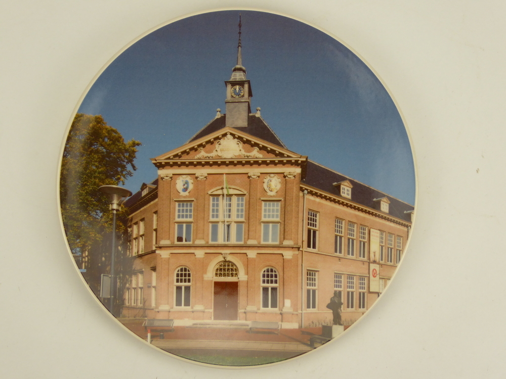 ronde aardewerken sierbord met afbeelding Veenkoloniaal Museum, gemaakt in 2023 voor en in opdracht van het Veenkoloniaal Museum. op achterzijde inscriptie: Veenkoloniaal Museum Veendam handmade in the Netherlands Royal Goudewaagen since 1610 en signatuur AR